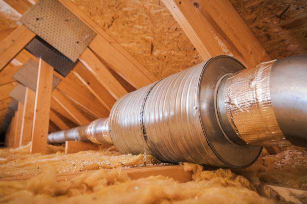 Attic ventilation system with metal ducting installed among insulation in a residential attic, emphasizing airflow optimization for energy efficiency and moisture control.