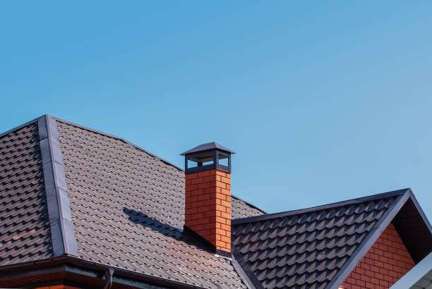 Roof with textured shingles and a brick chimney against a clear blue sky, illustrating quality roofing and chimney features relevant to Anvil Roofers' exterior services.
