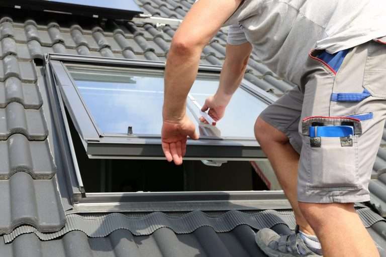 Worker installing a skylight on a tiled roof, demonstrating proper installation techniques for leak protection and natural light enhancement.